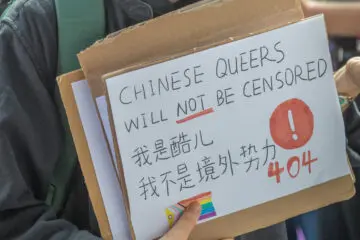 Person holds a bilingual handmade sign, it reads 'Chinese queers will not be censored'
