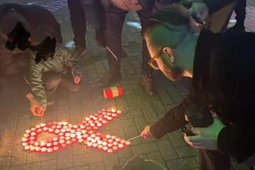 A group of people light candles at a memorial for World Aids Day