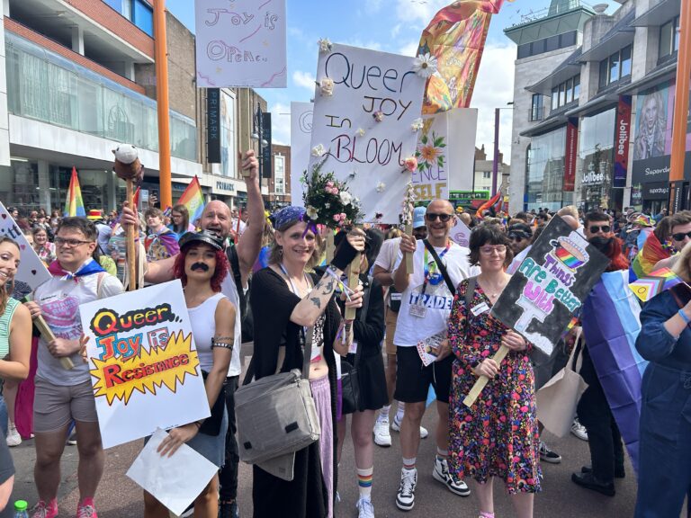 A large crowd of people holding placards and signs at a pride event